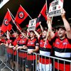 AFL Bomber fans standing in a cue to get into stadium, all are wearing red and black striped ...jpeg