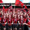 AFL Bomber fans standing in a cue to get into stadium, all are wearing red and black striped ...jpeg