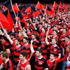 AFL Bomber fans standing in a cue to get into stadium, all are wearing red and black striped ...jpeg